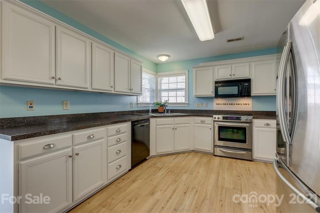 704 Beechnut Court Fort Mill, SC 29708 - Photo 12 of 46 a kitchen with granite countertop a stove top oven a sink dishwasher and a refrigerator with wooden floor