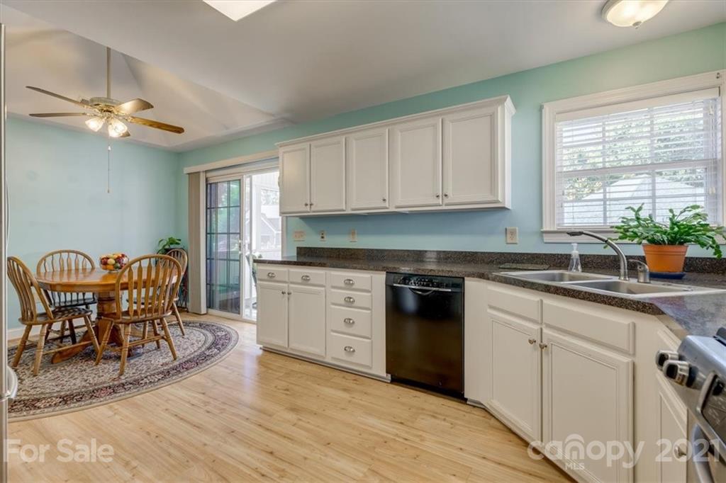 704 Beechnut Court Fort Mill, SC 29708 - Photo 14 of 46 a kitchen with granite countertop a stove a sink a dining table and chairs with wooden floor