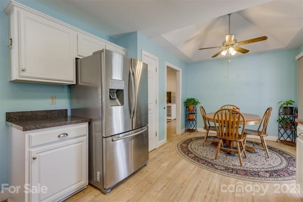 704 Beechnut Court Fort Mill, SC 29708 - Photo 15 of 46 a kitchen with granite countertop a refrigerator a stove a microwave a dining table and chairs with wooden floor