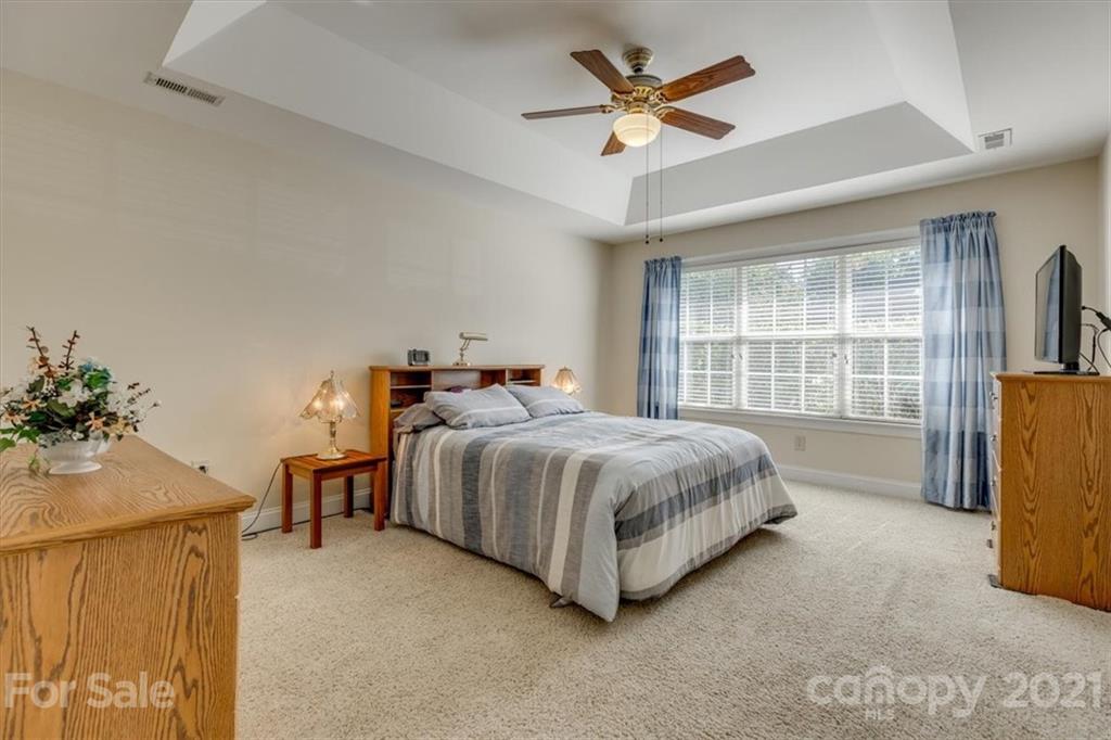 704 Beechnut Court Fort Mill, SC 29708 - Photo 27 of 46 a spacious bedroom with a bed a window and a chandelier