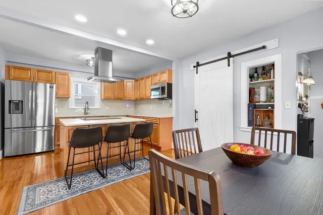 a kitchen with stainless steel appliances wooden floor dining table and chairs