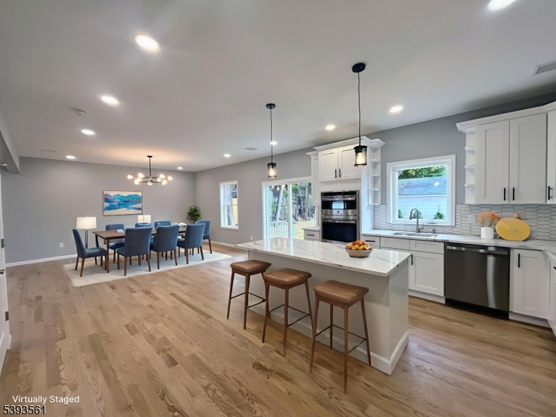 120 Addison Street Boonton, NJ 07005 - Photo 12 of 44 a kitchen with stainless steel appliances granite countertop a stove top oven a sink dishwasher a dining table and chairs with wooden floor