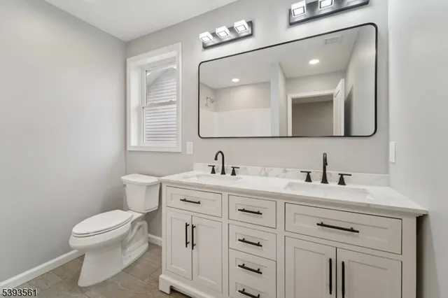 a bathroom with a toilet sink vanity and mirror