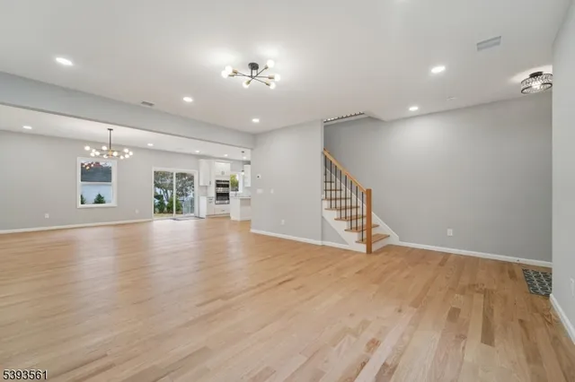 a view of an empty room with wooden floor and a kitchen