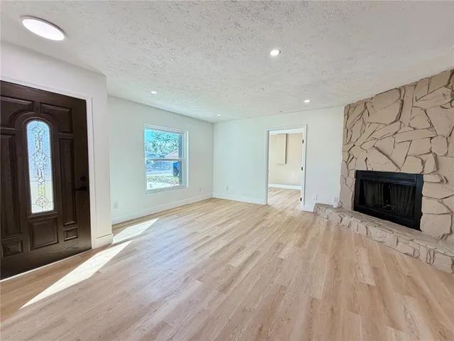 an empty room with windows and fireplace