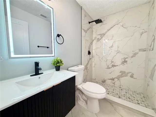 a bathroom with a sink a toilet and shower