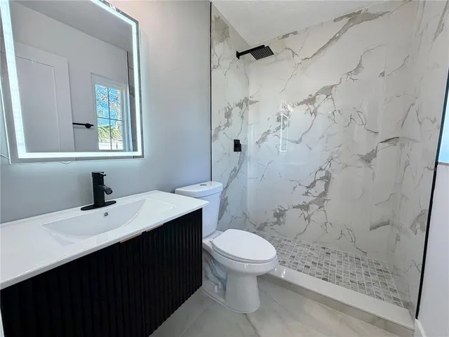 a bathroom with a sink a toilet a mirror and shower