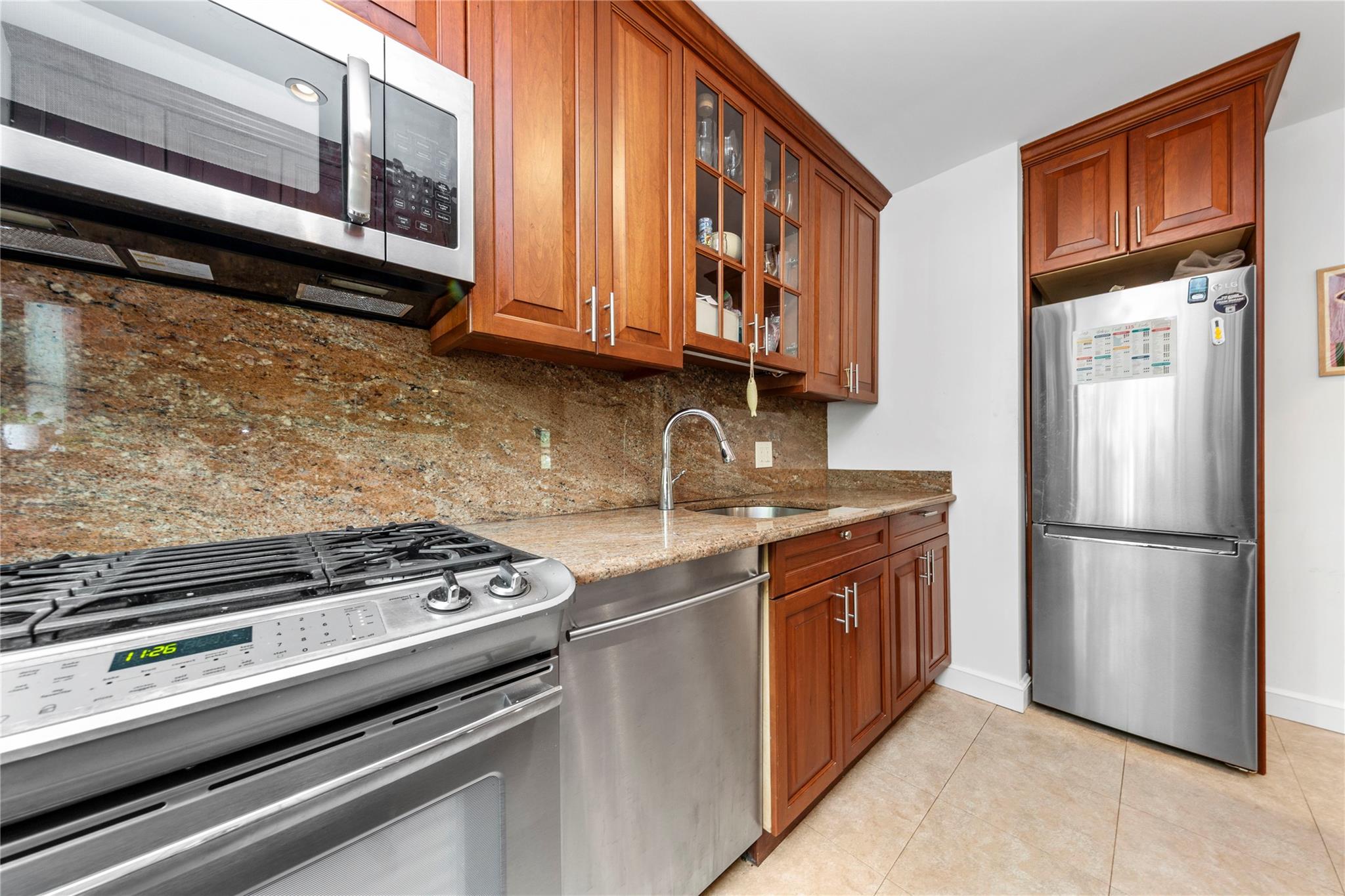 218-02 73rd Avenue, Unit UPPR Queens, NY 11364 - Photo 13 of 19 a kitchen with stainless steel appliances granite countertop a stove a refrigerator and a microwave