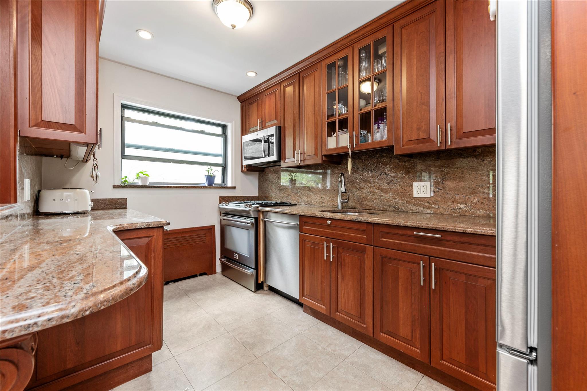 218-02 73rd Avenue, Unit UPPR Queens, NY 11364 - Photo 4 of 19 a kitchen with stainless steel appliances granite countertop wooden cabinets a sink and dishwasher