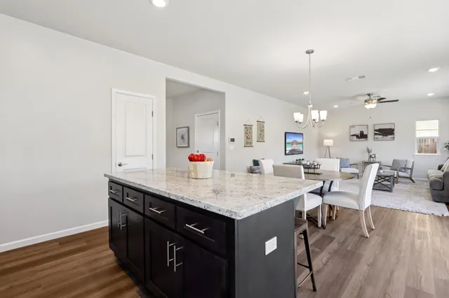 a dining hall with stainless steel appliances granite countertop a sink dishwasher and a dining table with wooden floor