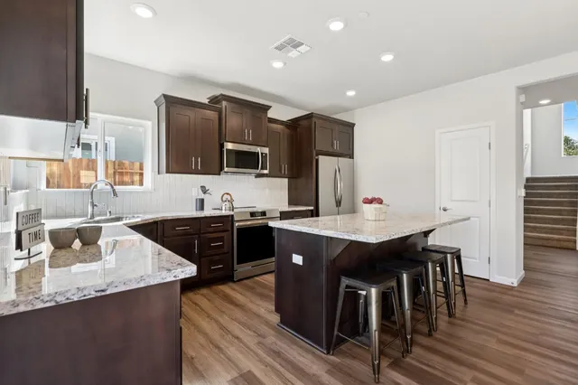 a kitchen with stainless steel appliances granite countertop a sink counter space and chairs