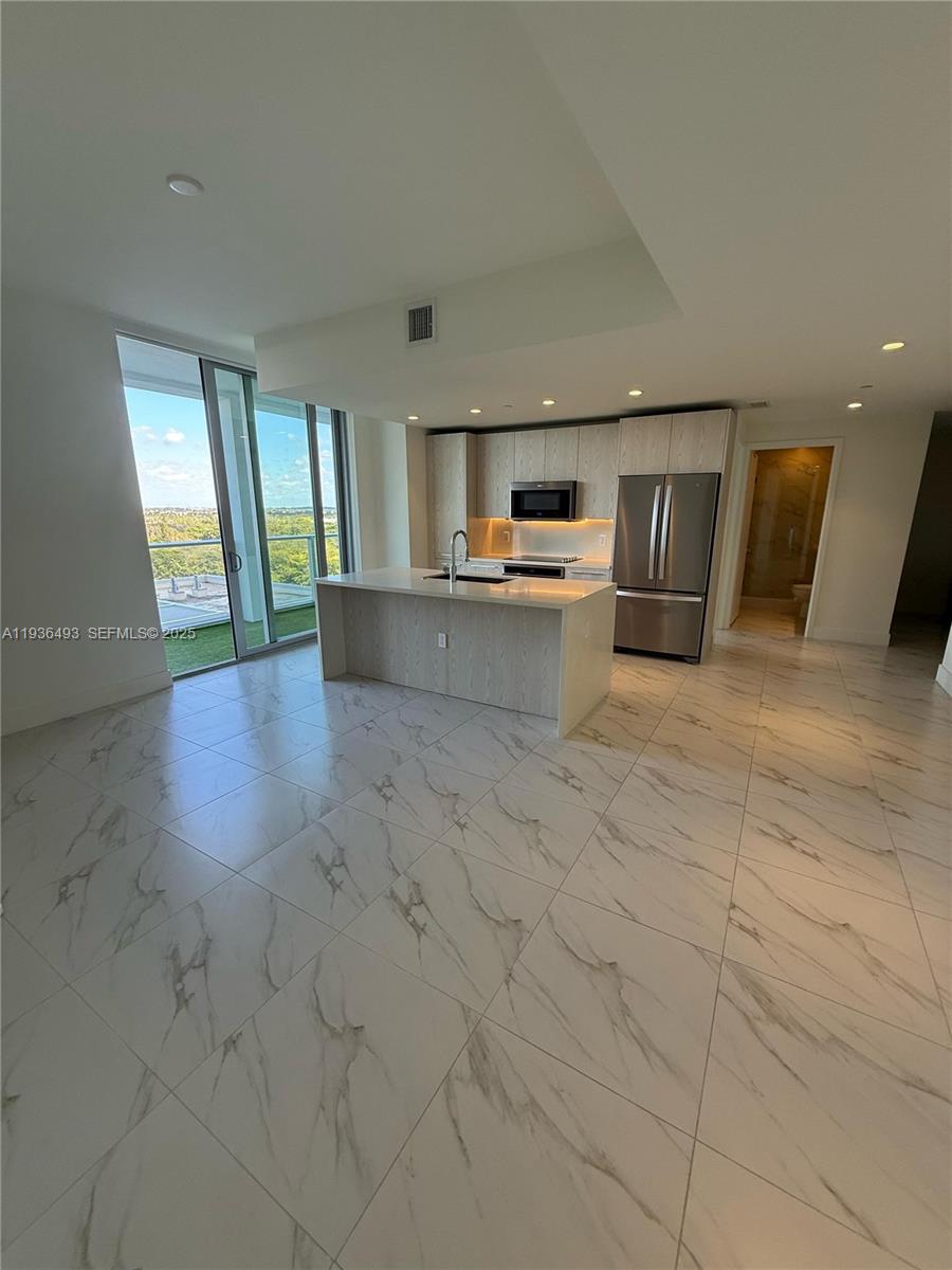 2000 Metropica Way, Unit 901 Sunrise, FL 33323 - Photo 9 of 19 a view of a electric appliances in kitchen and empty room with wooden floor