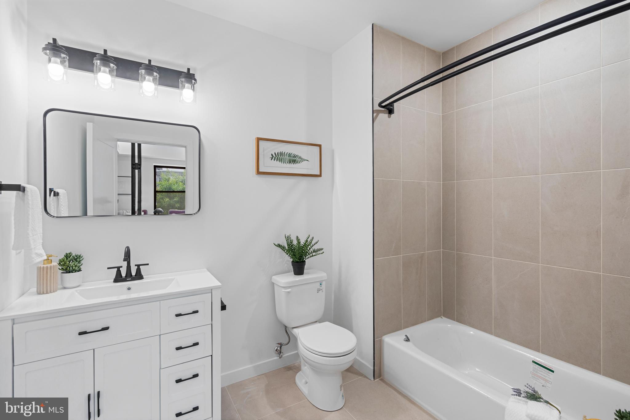 3211 Cedar Street, Unit 405 Philadelphia, PA 19134 - Photo 7 of 18 a bathroom with a toilet a sink a tub and mirror