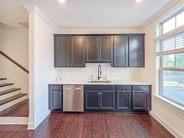 a kitchen with stainless steel appliances granite countertop wooden cabinets a sink and dishwasher with wooden floor