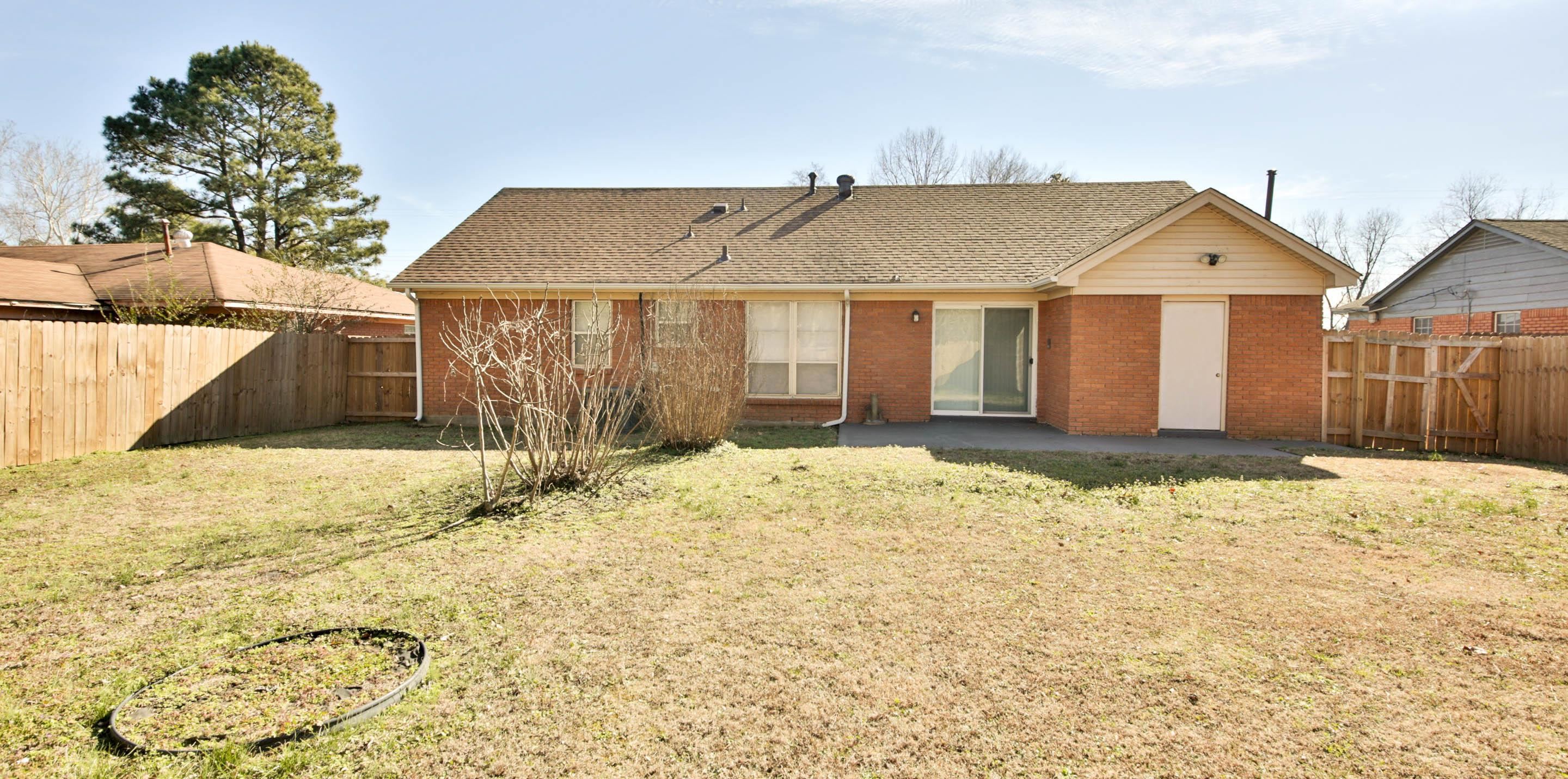 1820 West Holmes Road Memphis, TN 38109 - Photo 5 of 28 Rear view of house with brick siding, a fenced backyard, a patio area, and roof with shingles