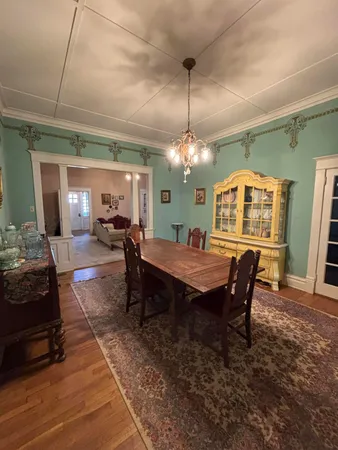 a dining room with wooden floor a chandelier a wooden table and chairs