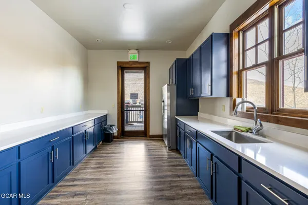 a kitchen with stainless steel appliances granite countertop wooden cabinets a sink and dishwasher a oven a large window with wooden floor