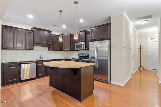 a kitchen with stainless steel appliances granite countertop a refrigerator a sink and a stove