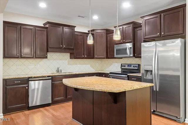 a kitchen with stainless steel appliances granite countertop a sink a stove a refrigerator and cabinets