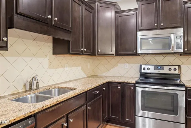 a kitchen with granite countertop a sink stainless steel appliances and cabinets