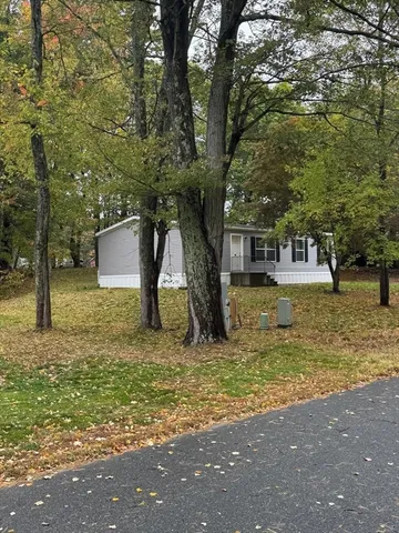 a large tree in front of a house with a yard
