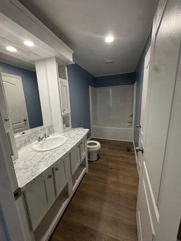a bathroom with a granite countertop sink a toilet and a large mirror