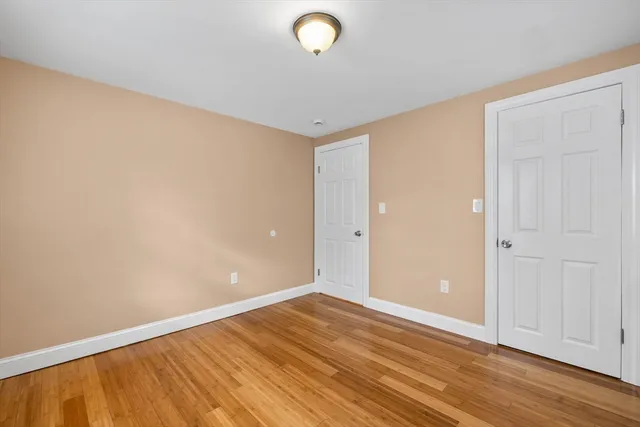 a view of an empty room with wooden floor and entryway