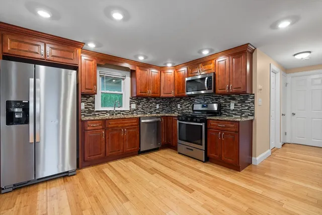 a kitchen with stainless steel appliances kitchen island granite countertop a stove refrigerator and cabinets