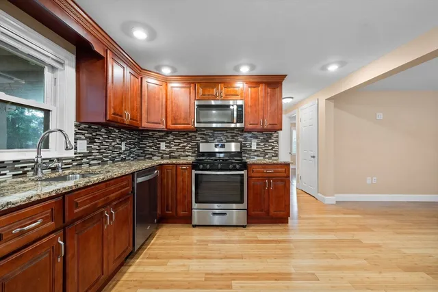 a kitchen with stainless steel appliances granite countertop a stove a sink and a microwave