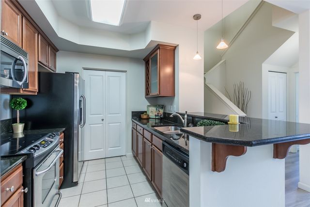 a kitchen with stainless steel appliances granite countertop a sink a stove and a refrigerator