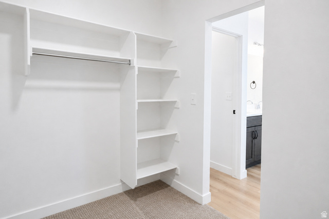 1004 West Paramount Cove South, Unit 315 Ogden, UT 84405 - Photo 21 of 42 Primary closet featuring built-in white shelving and hanging rod with carpeted flooring