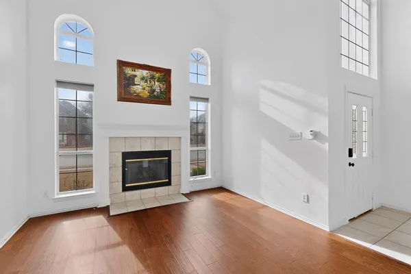 an empty room with wooden floor a fireplace and windows