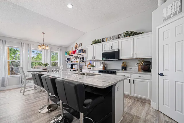 a kitchen with kitchen island granite countertop a sink cabinets and wooden floor