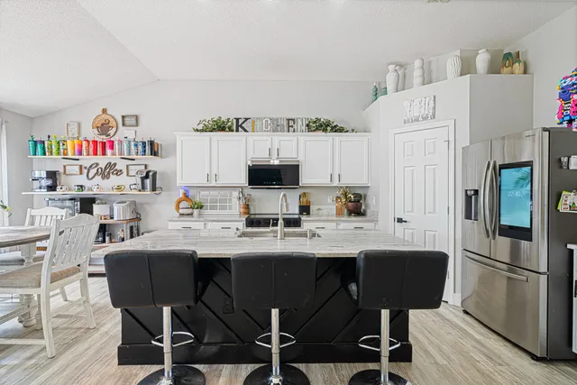 a kitchen with a dining table chairs refrigerator and sink