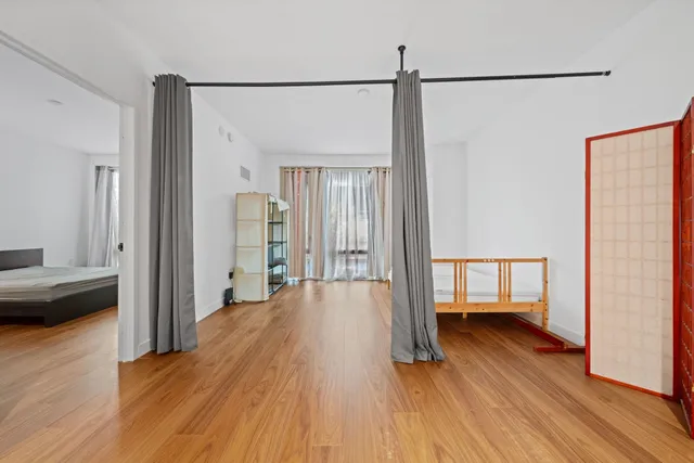a view of a bedroom with wooden floor and a balcony