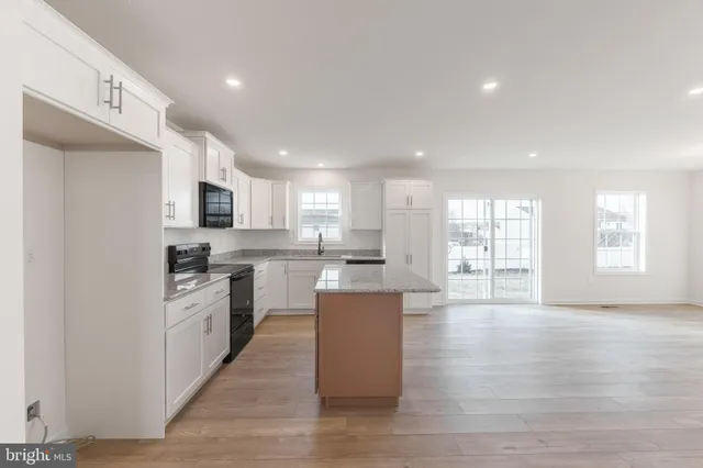 a large kitchen with a large counter top a sink stainless steel appliances and cabinets