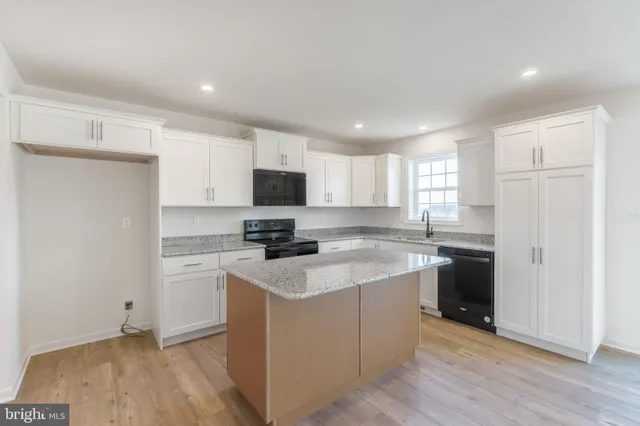 a kitchen with a sink a stove a refrigerator a window and white cabinets