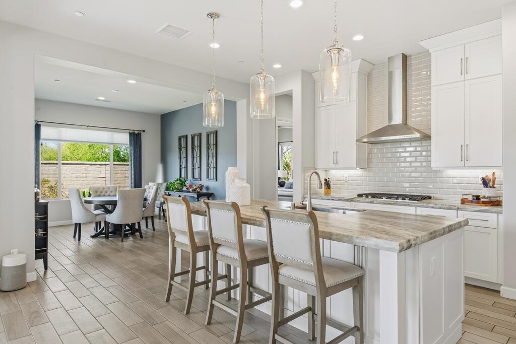 77 Barolo Rancho Mirage, CA 92270 - Photo 29 of 61 a kitchen with stainless steel appliances granite countertop a stove a sink dishwasher a couches chairs and a dining table with wooden floor