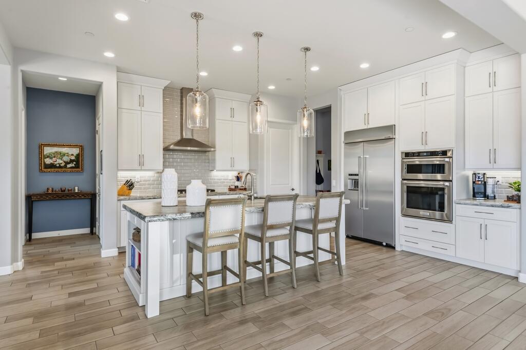 77 Barolo Rancho Mirage, CA 92270 - Photo 5 of 61 a kitchen with stainless steel appliances kitchen island granite countertop a refrigerator a stove a sink and white cabinets with wooden floor