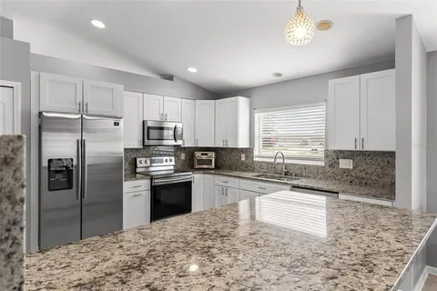 a kitchen with stainless steel appliances granite countertop a refrigerator sink and stove