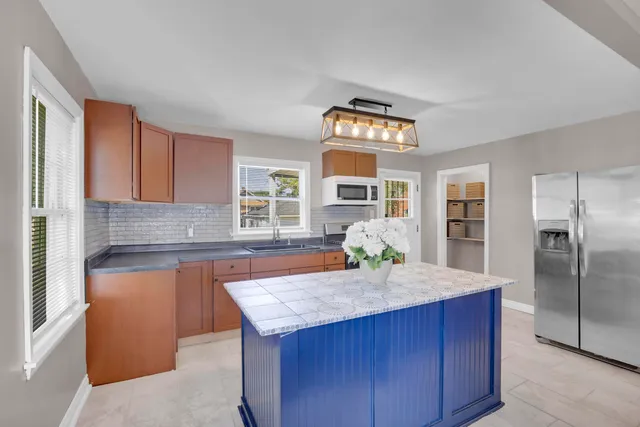 a kitchen with granite countertop kitchen island stainless steel appliances a sink and a refrigerator