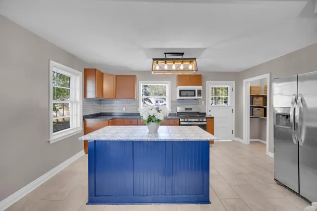 a kitchen with kitchen island granite countertop a refrigerator and a sink