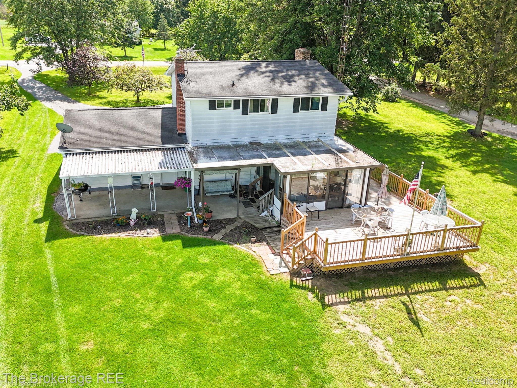 6129 East Lake Road Millington, MI 48746 - Photo 37 of 47 Back of property with a sunroom, a lawn, a chimney, a deck, and outdoor dining area