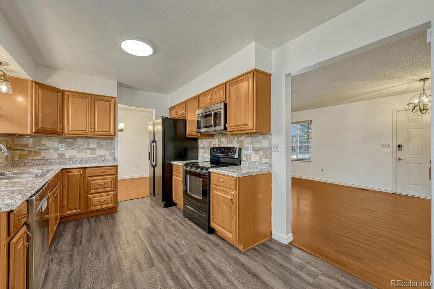 2079 South Quintero Street Aurora, CO 80013 - Photo 11 of 37 a kitchen with granite countertop wooden floors and stainless steel appliances