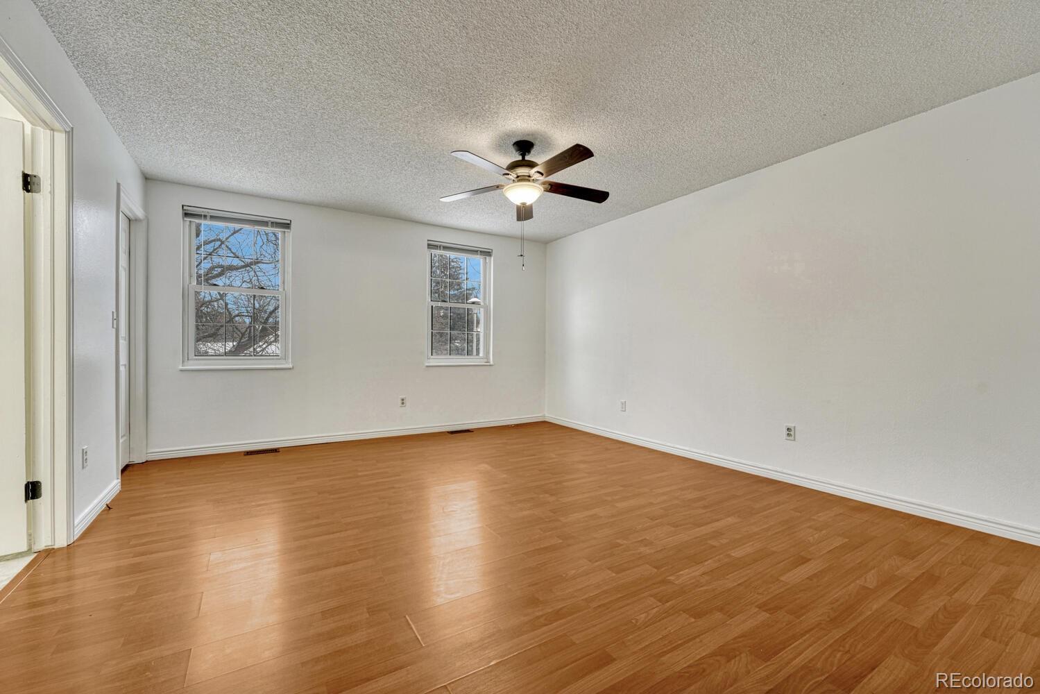2079 South Quintero Street Aurora, CO 80013 - Photo 20 of 35 an empty room with wooden floor chandelier fan and windows
