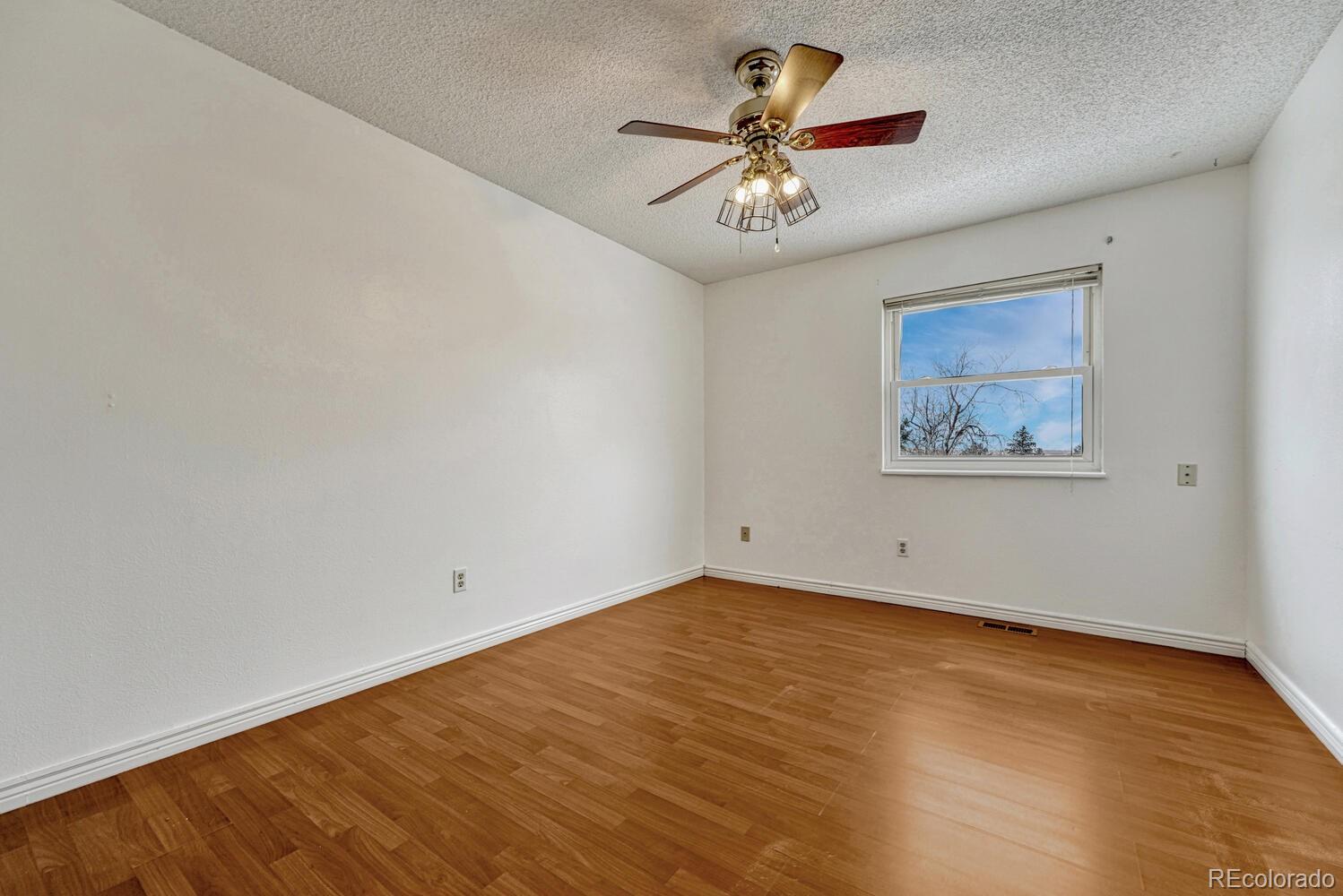 2079 South Quintero Street Aurora, CO 80013 - Photo 24 of 35 an empty room with a chandelier fan and wooden floor