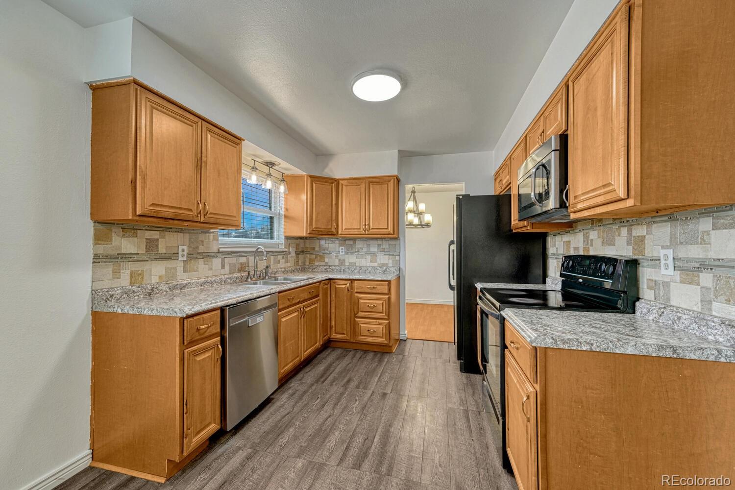 2079 South Quintero Street Aurora, CO 80013 - Photo 10 of 35 a kitchen with stainless steel appliances granite countertop wooden cabinets a stove a sink and a wooden floors