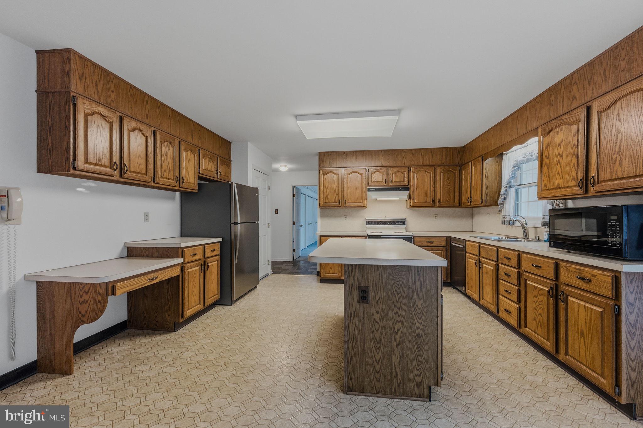 23 Raphael Road Hockessin, DE 19707 - Photo 16 of 44 a kitchen with stainless steel appliances kitchen island granite countertop a stove top oven a sink dishwasher a dining table and chairs with wooden cabinets