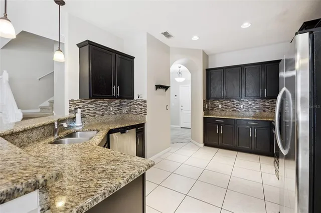 a kitchen with stainless steel appliances kitchen island granite countertop a sink stove and refrigerator