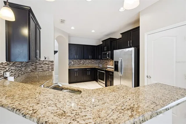 a kitchen with stainless steel appliances kitchen island granite countertop a refrigerator and a sink